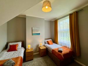 a bedroom with two beds and a window at Waterloo House - Urban Oasis Townhouse in Nottingham
