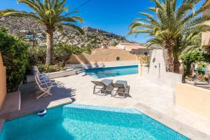 een zwembad met palmbomen en een villa bij Casa Veintiuno en Calp in Calpe