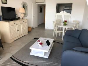 een woonkamer met een blauwe bank en een tafel bij Grand F1 face à la plage, Climatisé, parking, grand confort 4 pers in Propriano