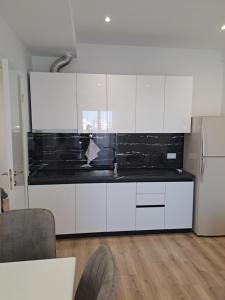 a kitchen with white cabinets and black counter tops at Erdis Home Nr 1 in Tirana