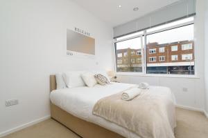 a white bedroom with a bed and a window at Brightway Hemel, WiFi and Netflix, Perfect for Contractors and Relocators in Hemel Hempstead