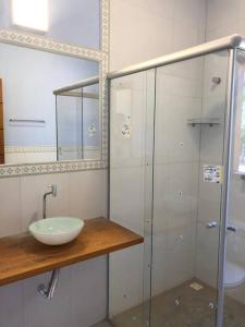 a bathroom with a sink and a glass shower at Belíssima casa no condomínio Mar Doce de Abrolhos in Caravellas