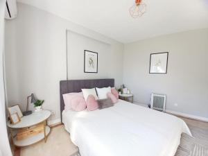 een witte slaapkamer met een groot bed met roze kussens bij Feliz Algarve in Albufeira