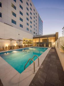 a pool in a hotel with tables and chairs at Courtyard by Marriott Chihuahua in Chihuahua