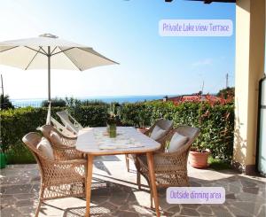 einen Tisch und Stühle mit Sonnenschirm auf einer Terrasse in der Unterkunft Panorama lake view, pool & garden, 2 bathrooms, kingsize & single-beds, fast Internet in Toscolano-Maderno