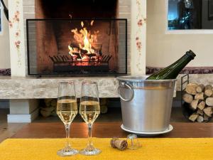 two glasses of wine on a table with a fireplace at Pousada Kaliman Premium in Campos do Jordão