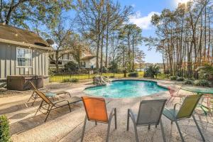 a backyard with a pool with chairs and a table at Cypress Grove - Dog River in Mobile