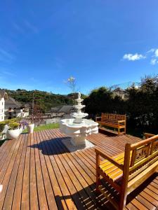 une terrasse en bois avec une fontaine et deux bancs dans l'établissement Pousada Kaliman Premium, à Campos do Jordão