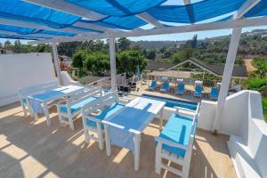 un patio con mesas y sillas azules y una piscina en Sisyphos Hotel, en Gelemiş