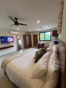 uma grande cama branca num quarto com uma televisão de ecrã plano em New Studio p/2, jacuzzi, alberca, roof top em Tulum