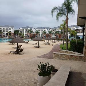 een resort met tafels en parasols en een zwembad bij The Luxe Marvelous Apartment in Pretoria