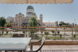 uma mesa e cadeiras numa varanda com vista para um edifício em Nefeli City Apartments em Patra