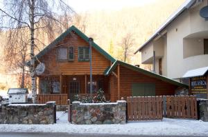 een houten huis met een hek in de sneeuw bij Brvnara Bjelasica in Kolašin