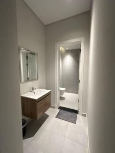 een badkamer met een wastafel, een toilet en een spiegel bij Almajdiah Village Luxury Self-entry Al Malqa in Riyad