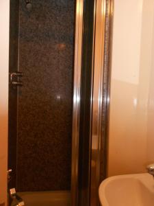 una ducha con una puerta de cristal junto a un lavabo en 24/7 London Hostel, en Londres