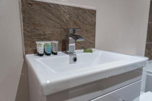 a white bathroom sink with two toothbrushes on it at Modern Manchester Apartment, Free Parking For Two, Smart TVs, Central Location in Manchester