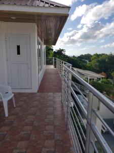 un balcone di una casa con porta bianca di JEMMROSE SUITES a Choc