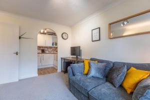 a living room with a blue couch and yellow pillows at Chic Flat in Woolston: Nr Southampton City Centre in Southampton