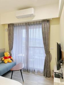 a teddy bear sitting on a couch in front of a window at Ｎ 24.8 二館-宜蘭頭城民宿 in Toucheng