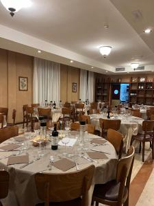 una stanza con tavoli e sedie con tovaglie bianche di Hotel President a Montecatini Terme