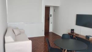 a living room with a table and a white couch at Apartamento Vista Farol da Barra com 2 Quartos in Salvador