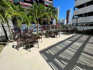 eine Terrasse mit Tischen, Stühlen und Palmen in der Unterkunft UNU Salvador Shopping in Salvador