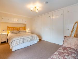 a bedroom with a bed with white cabinets and a chair at 1 Bed in Newton Stewart DF198 in Newton Stewart