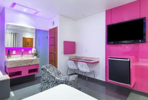 baño rosa con lavabo y TV en Motel Fashion ABC 4, en Santo André