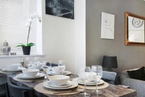 a dining room table with plates and wine glasses at 2 Bed Garden Flat Sleeps 6 Close to Brixton in London