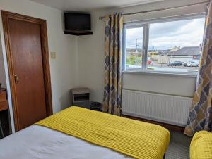 a bedroom with a bed with a yellow blanket and a window at Fairy Bridge Lodge in Bundoran