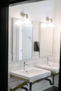 two sinks in a bathroom with two mirrors at Saintlo Ottawa Jail Hostel in Ottawa