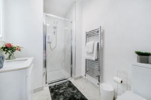 a white bathroom with a shower and a sink at 2 Bed Garden Flat Sleeps 6 Close to Brixton in London