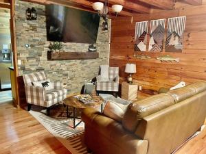 a living room with a leather couch and a stone wall at Clover Creek Cabin in Waynesville