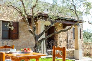 una mesa y sillas frente a una casa con un árbol en VILLA ISOLOTTO a 150 m dal mare, en Santa Maria Navarrese
