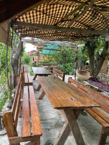 grupa drewnianych ławek siedzących pod pergolą w obiekcie Parsamyan's Art and Craft house w mieście Tekher