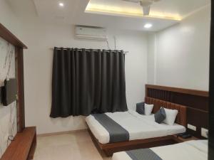 a bedroom with two beds and a black curtain at Hotel Nandan in Shegaon