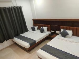 duas camas num quarto com cortinas pretas em Hotel Nandan em Shegaon