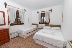 a bedroom with two beds and a dresser and windows at Calma Di Mare in Nea Kalikratia