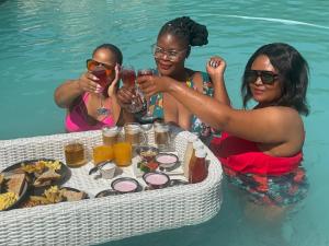 três mulheres a beber vinho na piscina em Africa Paradise - OR Tambo Airport Boutique Hotel em Benoni