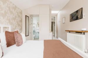 a white bedroom with a large bed and a bathroom at Luxury King-bed Ensuite With Tranquil Garden Views in London