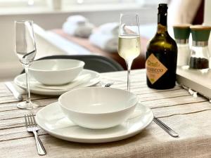 a table with two white plates and glasses of wine at Luxury King-bed Ensuite With Tranquil Garden Views in London