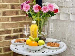 einen Tisch mit Obstteller und einer Vase aus Blumen in der Unterkunft Luxury King-bed Ensuite With Quiet Private Patio in London