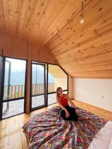 a woman sitting on a bed in a room with windows at Happy days house in Shuakhevi