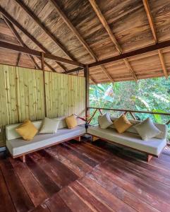 Habitación con 2 sofás en el suelo de madera. en Casa Prana, Termales, Nuqui, en Nuquí