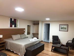 une chambre d'hôtel avec un lit et une chaise dans l'établissement Pousada Kaliman Premium, à Campos do Jordão