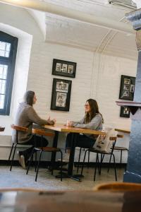 twee vrouwen aan een tafel in een kamer bij Saintlo Ottawa Jail Hostel in Ottawa