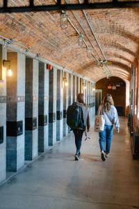 two women walking down a hallway in a building at Saintlo Ottawa Jail Hostel in Ottawa