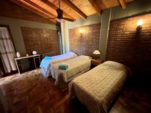 um quarto com 2 camas e uma parede de tijolos em Casa Don Molina, en Chacras con pileta! em Luján de Cuyo