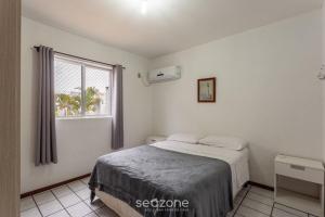 Schlafzimmer mit einem Bett und einem Fenster in der Unterkunft Apto Vista para a Praia em Canasvieiras SEN0105 in Florianópolis