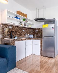 eine Küche mit einem Kühlschrank und einer blauen Couch in der Unterkunft BUDDA HOME in Tortuguero